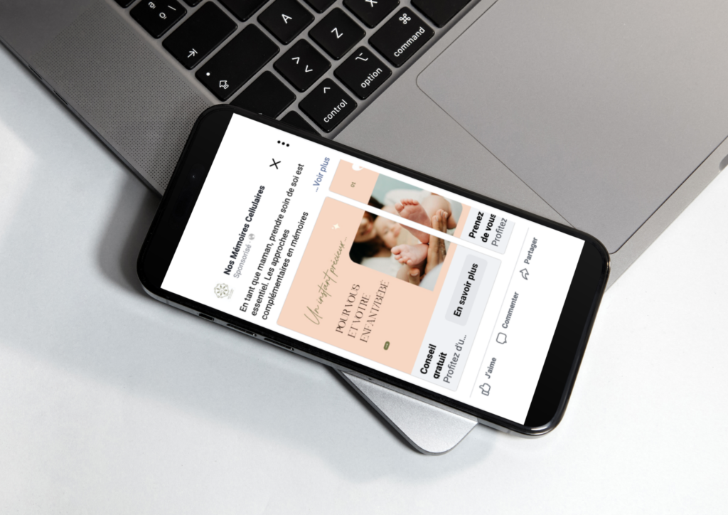 Un smartphone déposé sur le bord d'un ordinateur affichant une publicité Facebook à l'écran